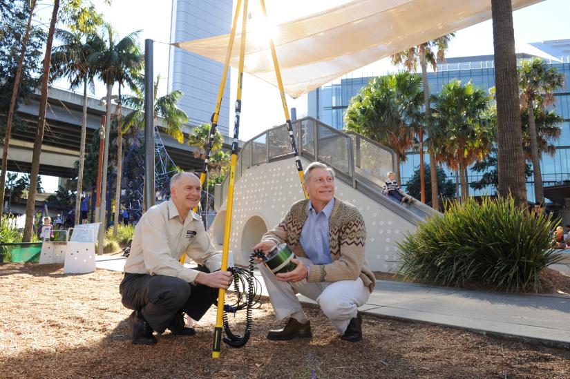 Two men crouched with measuring equipment at a Sydney playground