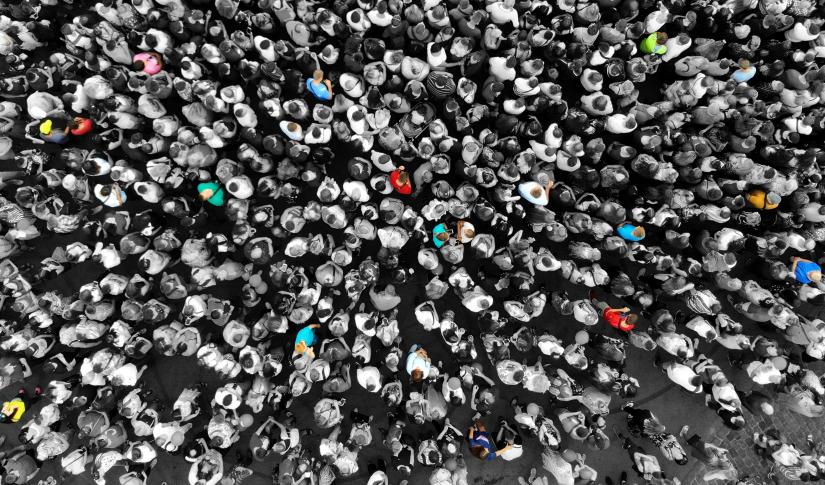 Special people amid the crowd concept with colorful persons amid the monochrome people. Top view from drone. 