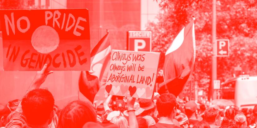 Protest with signs that read: 'No Pride in Genocide' on an Indigenous flag, and 'Always was, always will be, Aboriginal land'.