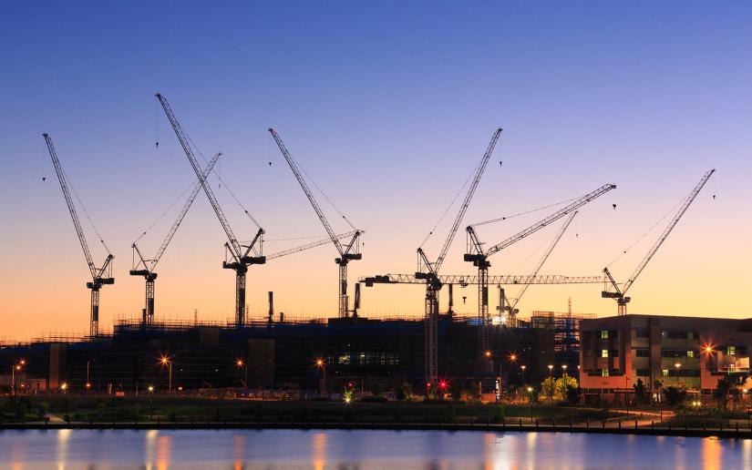 Construction cranes on buildings at dusk