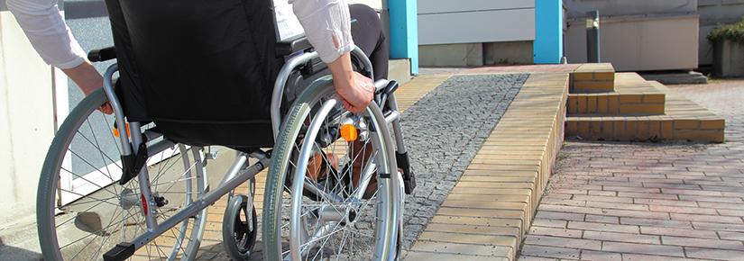 Stock image of a person in a wheelchair ascending a ramp at a private home