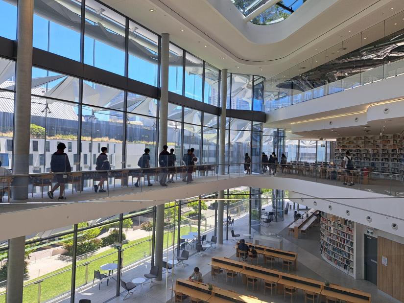 Image of interior of UTS Library, with high school students walking along the walkway beside the glass windows.