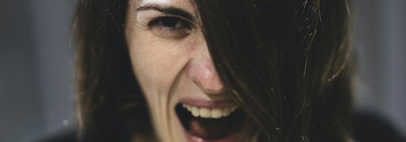 A woman screams while looking down barrel of the camera.