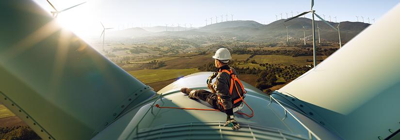 Technician sitting atop a large wind turbine in a wind farm