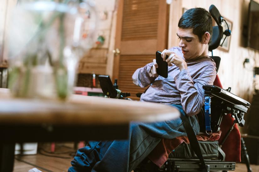 Stock picture of a young man with physical disabilities using mobile technology