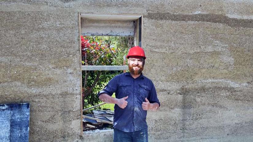 Peter Irga gives the thumbs up in front of a hempcrete wall