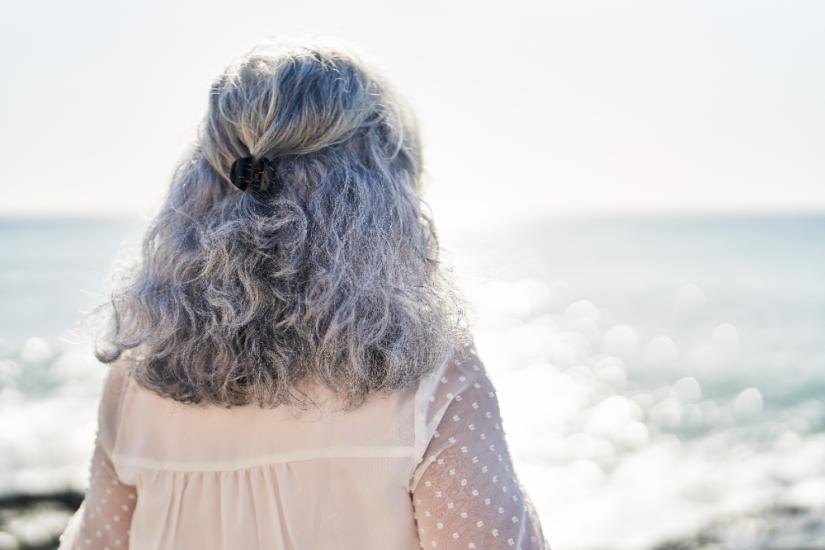 Middle age woman standing on back view at seaside. Image: Adobe Stock
