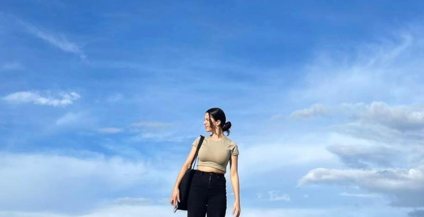 image of young woman standing against a blue sky background and looking to the side