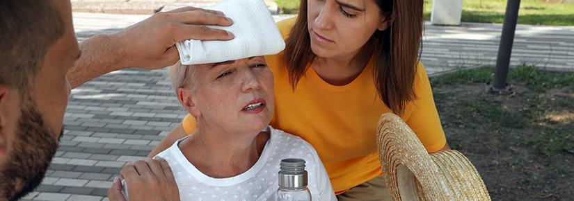 Stock picture of a woman suffering heat stroke being tended to by two other people 