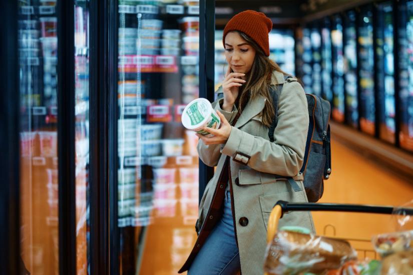 Woman checks food labels in the supermarket. Image: Adobe Stock