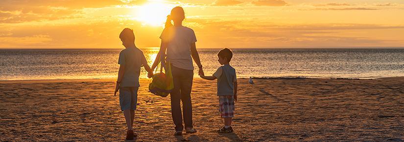Stock picture of a mother and two children on a beach at sunset