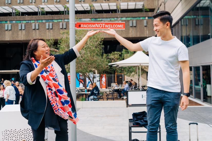 Dr Elaine Laforteza and Kurt Cheng smiling with the #RacismNotWelcome sign at UTS.