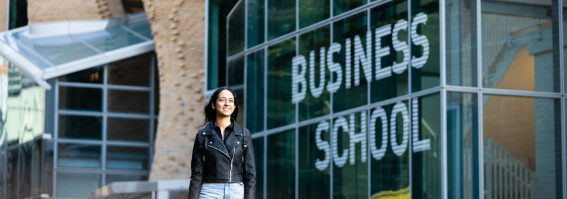 Female student standing in front of the business school