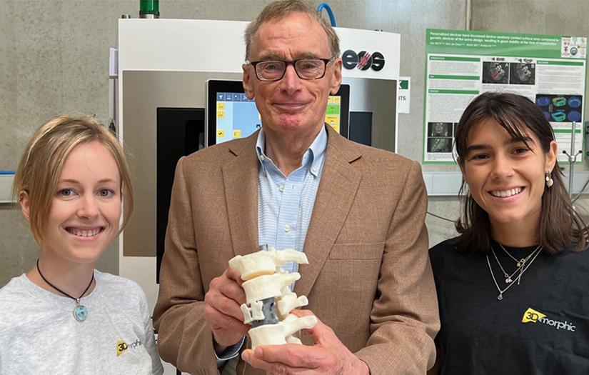 Bob Carr holding a portion of 3D printed vertebra with two UTS graduates Jess and Amaro standing on either side of him smiling.