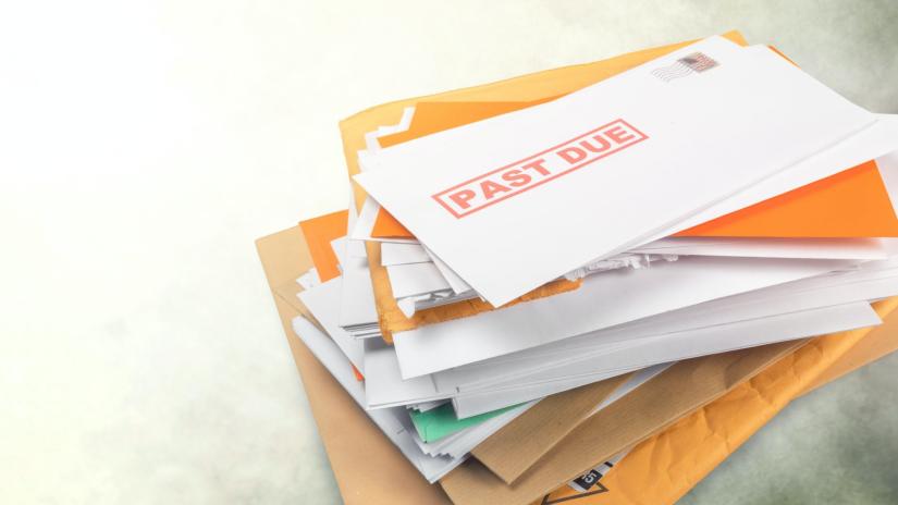 Stock picture of a pile of mail with an overdue notice on the top