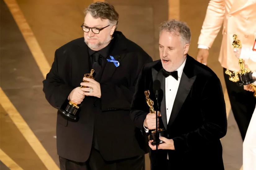 Guillermo del Toro receives an Oscar, stands on stage holding his award