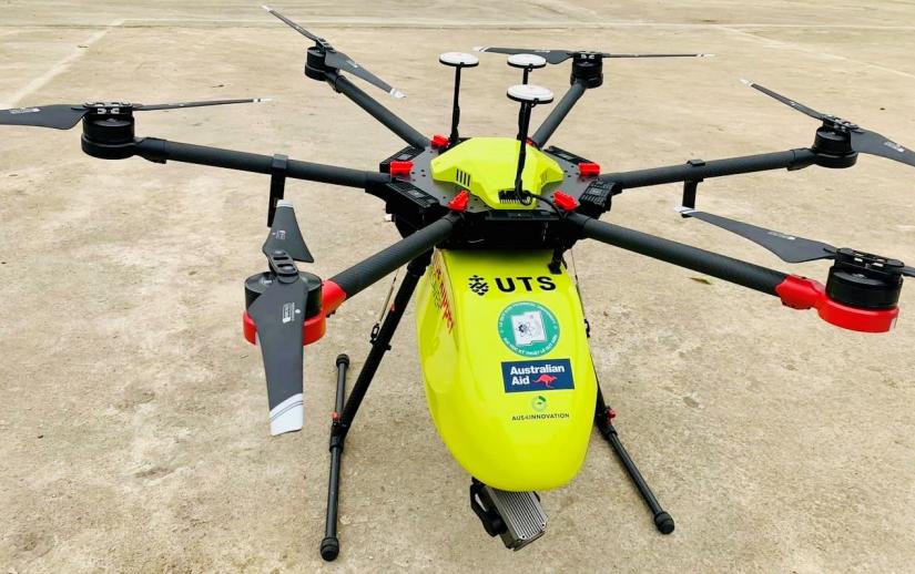 A neon yellow drone with 8 rotors sits on ground.