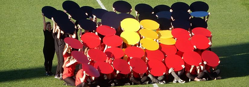 A group of people form an Indigenous flag using coloured cards at the Indigenous AFL round at the Adelaide Ova in June 2018. Picture by Michael Coghlan on Flickr (CC BY-SA 2.0)