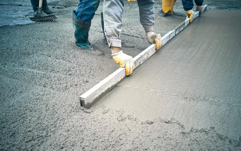 a construction worker levels wet concrete with a tool.