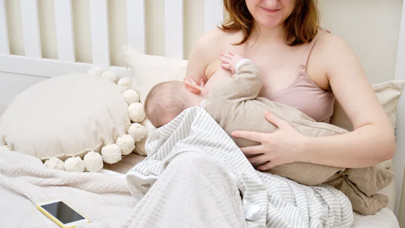 Person sitting on a sofa breastfeeding a baby.
