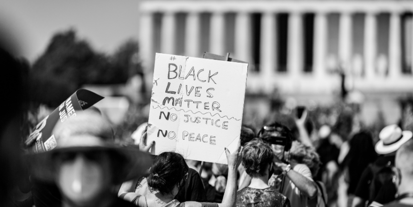 Image of a protest with a protestor holding a poster saying black lives matter