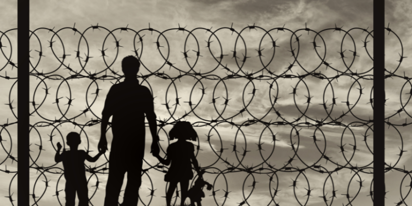 Silhouette of a father holding his children' hand, whilst being behind barb wires
