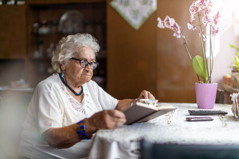 An older woman sits at a table reading