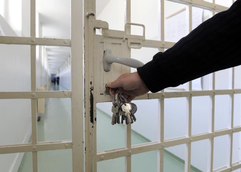 A hand locks a prison gate