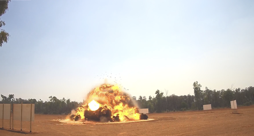 The moment of explosion - a fireball surrounded by a red dirt clearing