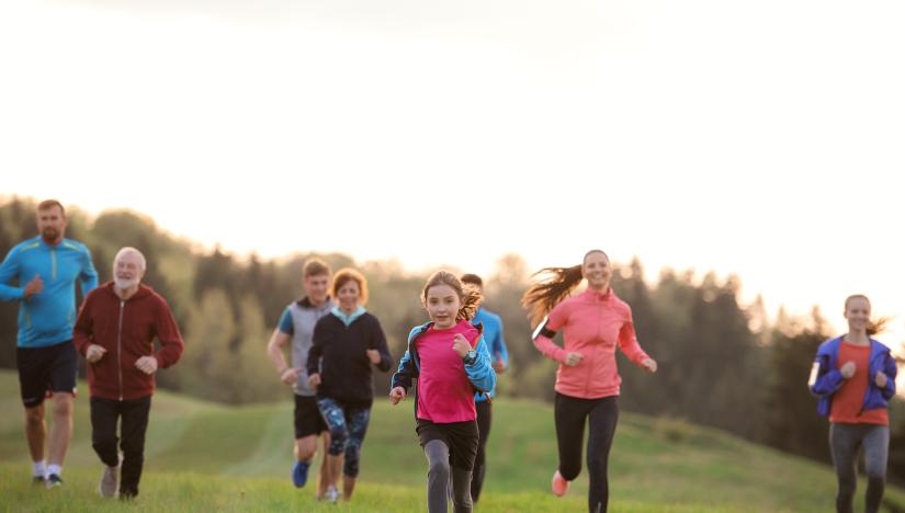 Stock picture of a group of adults and children exercising outdoors