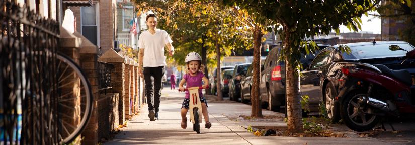 Child rides a bike down a city path