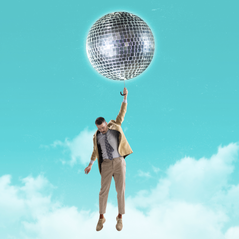 A man hangs from a handle extending out of a disco ball set amidst an open blue sky