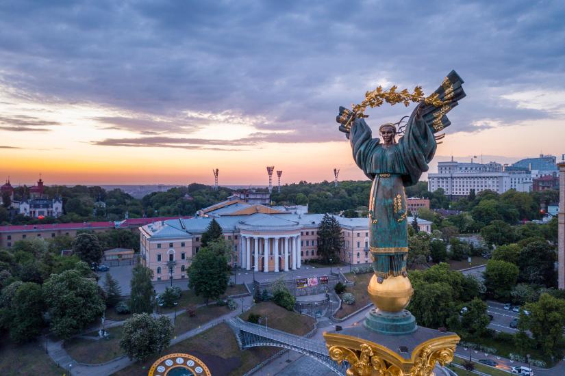 Monument of Independence Statue in Kyiv, Ukraine, above the square with the sun setting in the background.