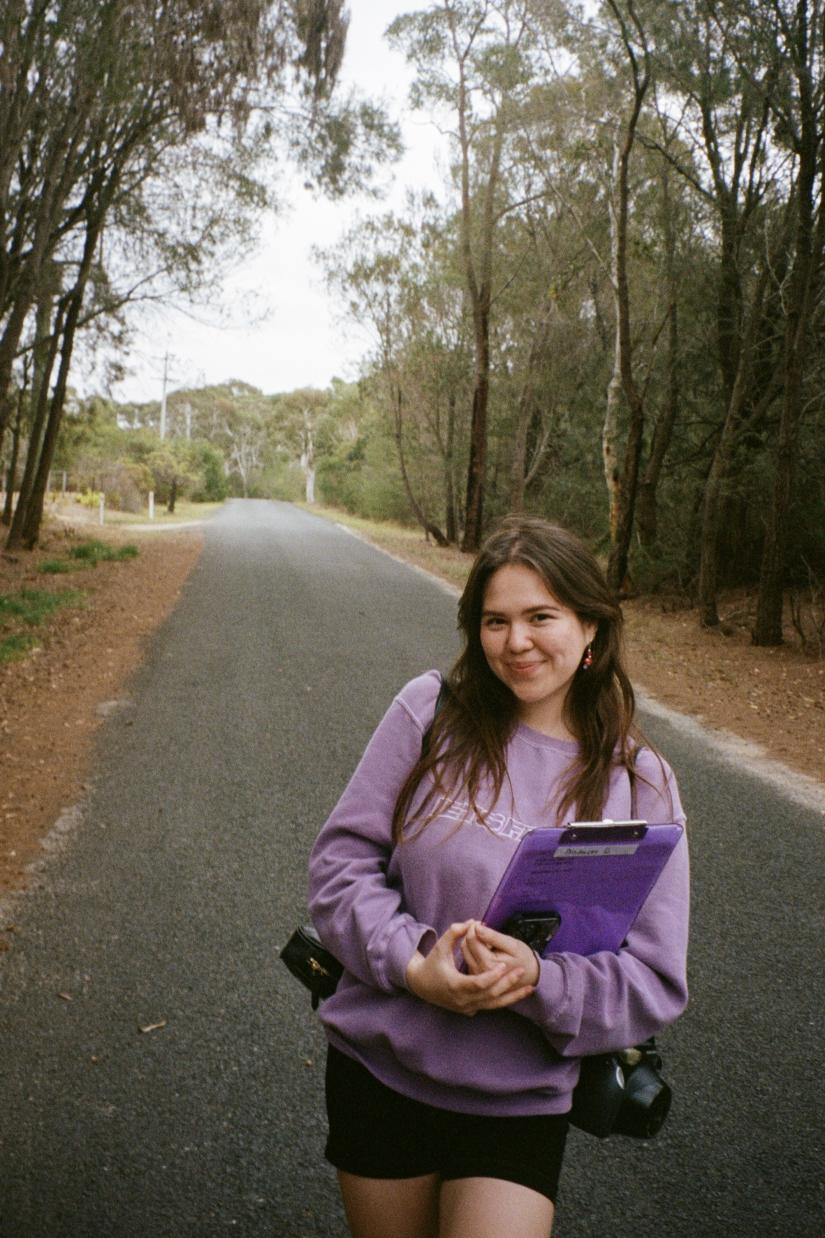Emma smiles for the camera while holding a clipboard on a country road