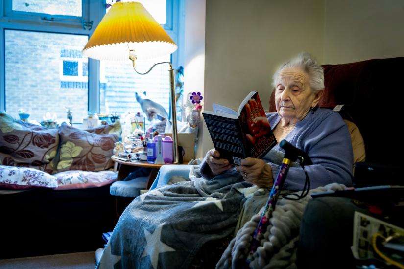 Rights free picture of an elderly woman reading in a chair with a blanket over her knees