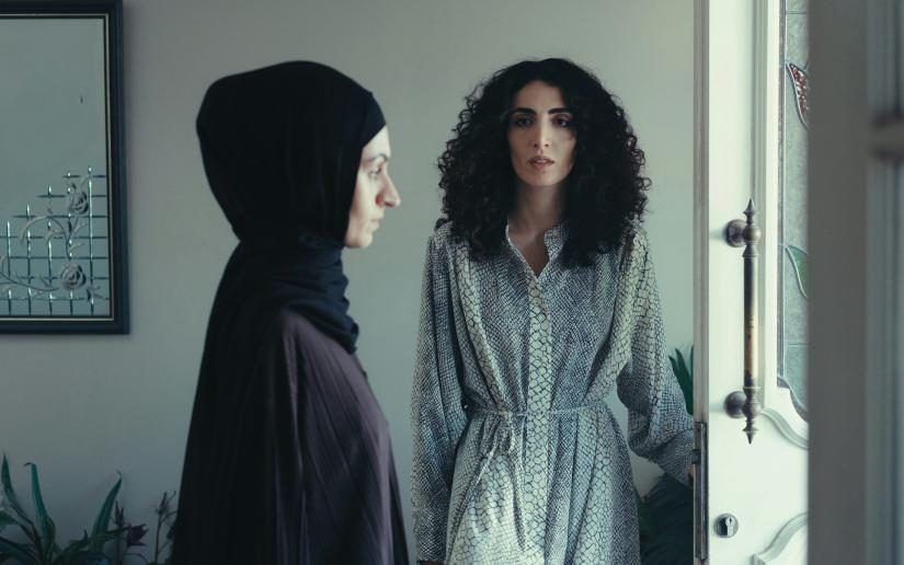 A production still from ABC's House of Gods with two women standing near the open front door of a residence