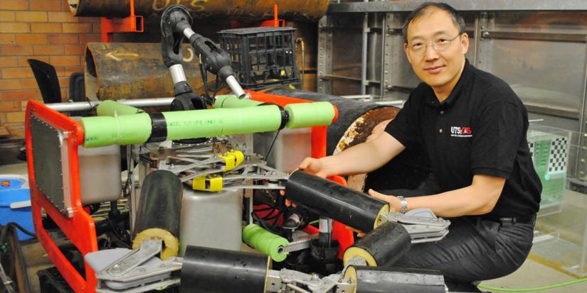 UTS Professor Dikai Liu crouches with one of his robotic devices