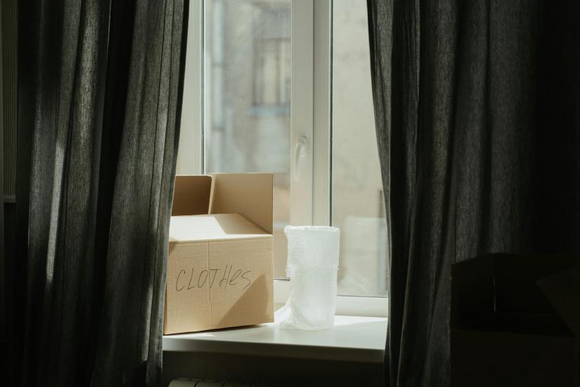 A cardboard box marked 'clothes' sits on a windowsill.
