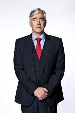 Photo of Shaun Micallef in suit with red tie