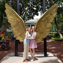 Velvet-Belle hugging her mum in front of a sculpture of giant pair of wings