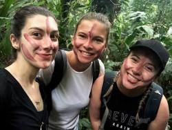 Alayna and two female friends with painted faces in the jungle