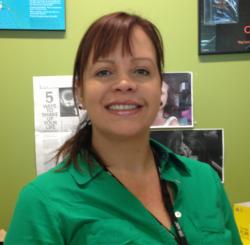 image of woman with long brown hair in a ponytail. she is wearing a green shirt. she is smiling at the camera