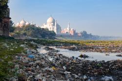 Indias contrast of ugly pollution and stunning beauty, The banks of Yamuna River polluted with garbage and beautiful Taj Mahal in the background
