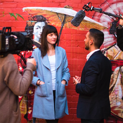 Student being interviewed on camera, colourful mural background