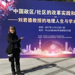 Carolyn Cartier in front of a poster for a conference in China