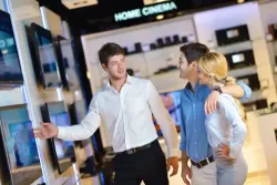 Image of a salesperson in a camera store interacting with two customers 
