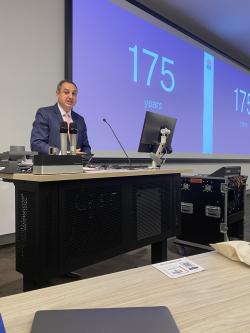 Man stands at lecture room lectern and speaks