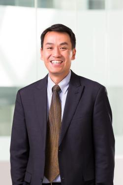 Professor Brian Le wearing a navy blue suit and smiling at the camera