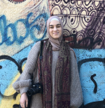 Hanan standing in front of a graffiti wall