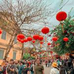 People walk the street celebrating Lunar New Year under red lanterns